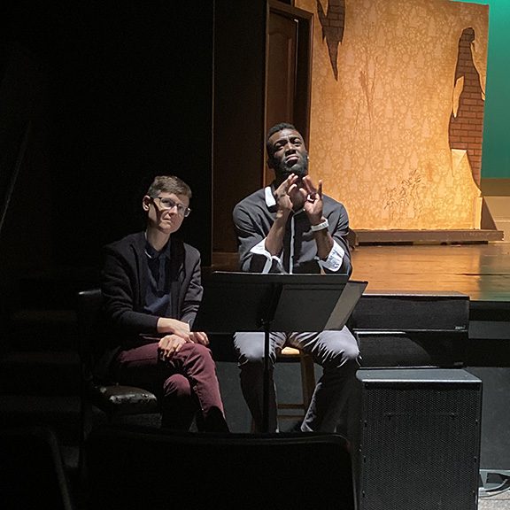 Two ASL interpreters seated at a music stand beside the stage during a CTA performance