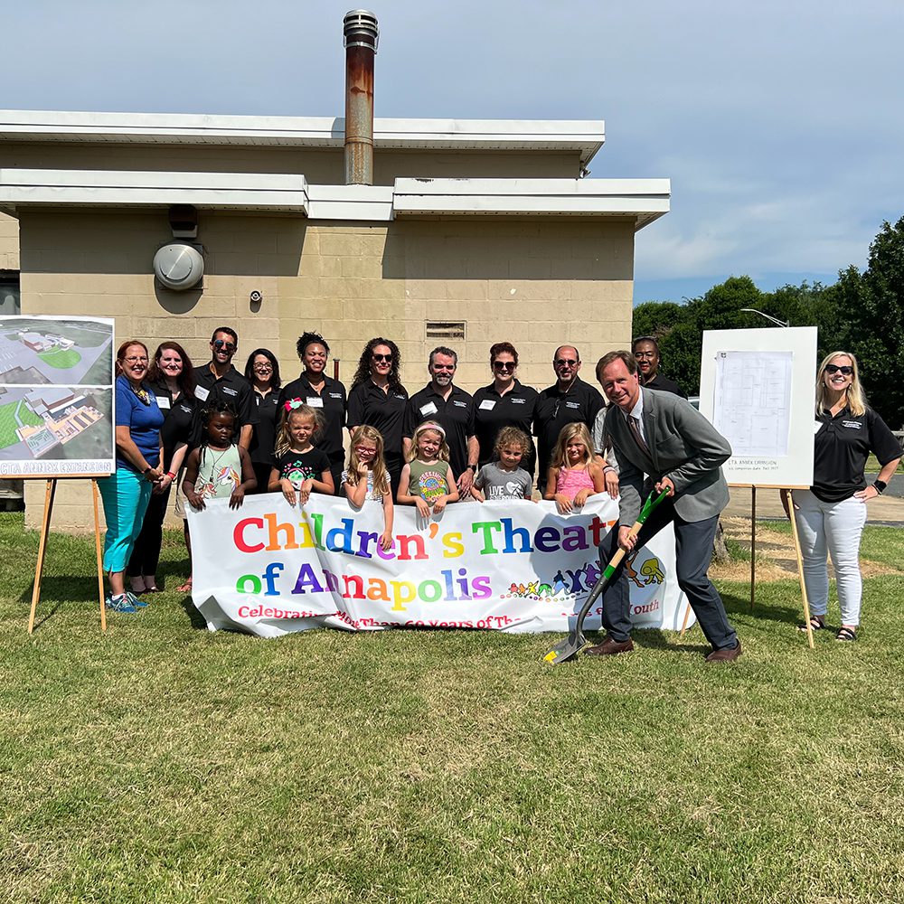 CTA members and supporters gather behind a Children's Theatre of Annapolis banner at the 2022 facility groundbreaking