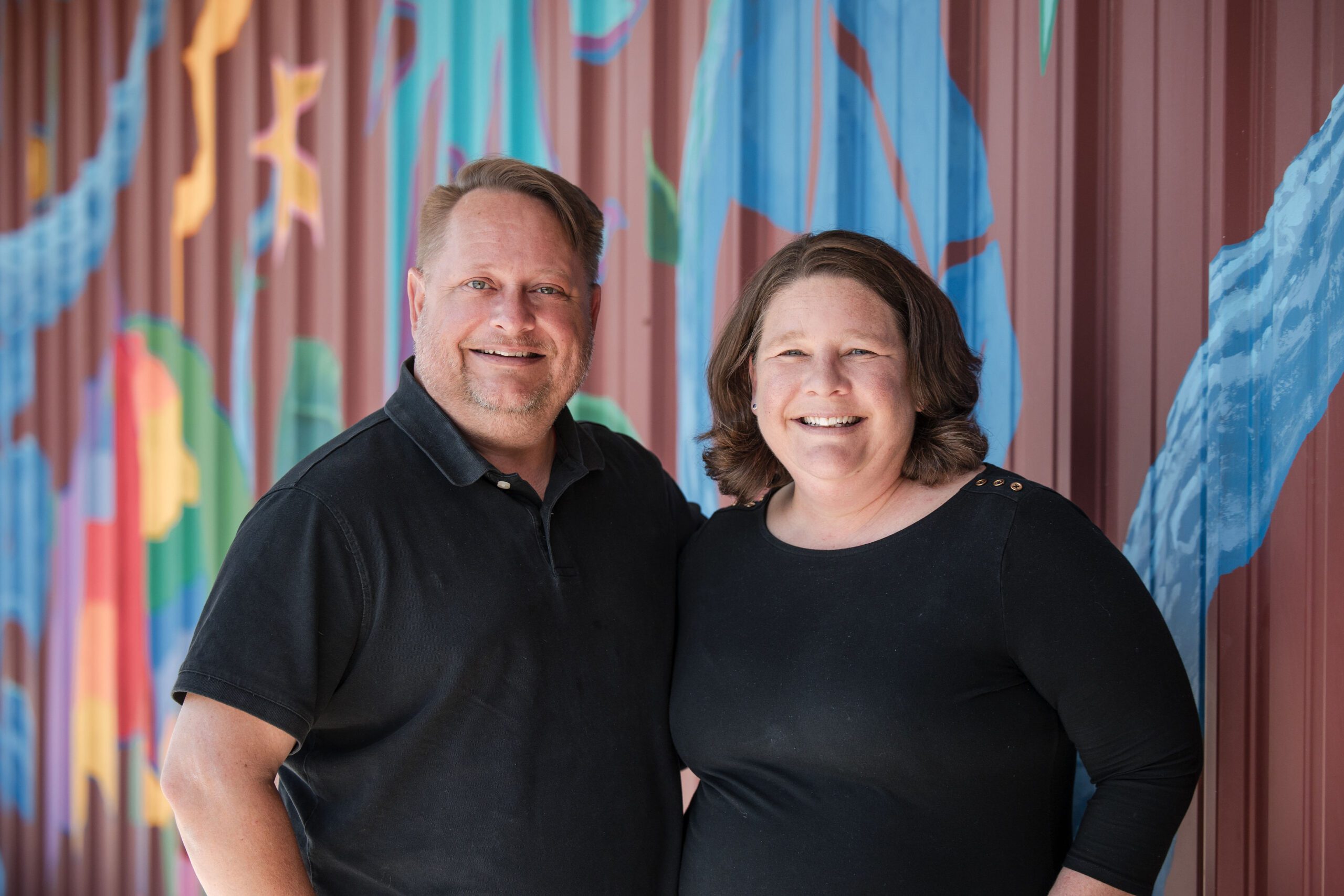 CTA Executive Directors Jason Kimmell and Amy Schropp standing in front of a colorful mural