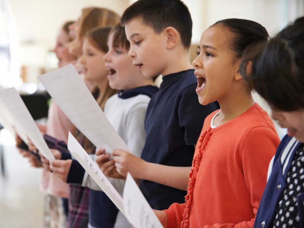 Children sing together while reading from sheet music